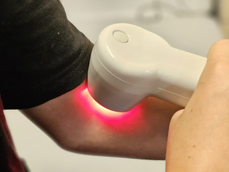 Child receiving red light therapy treatment on their forearm at a wellness center